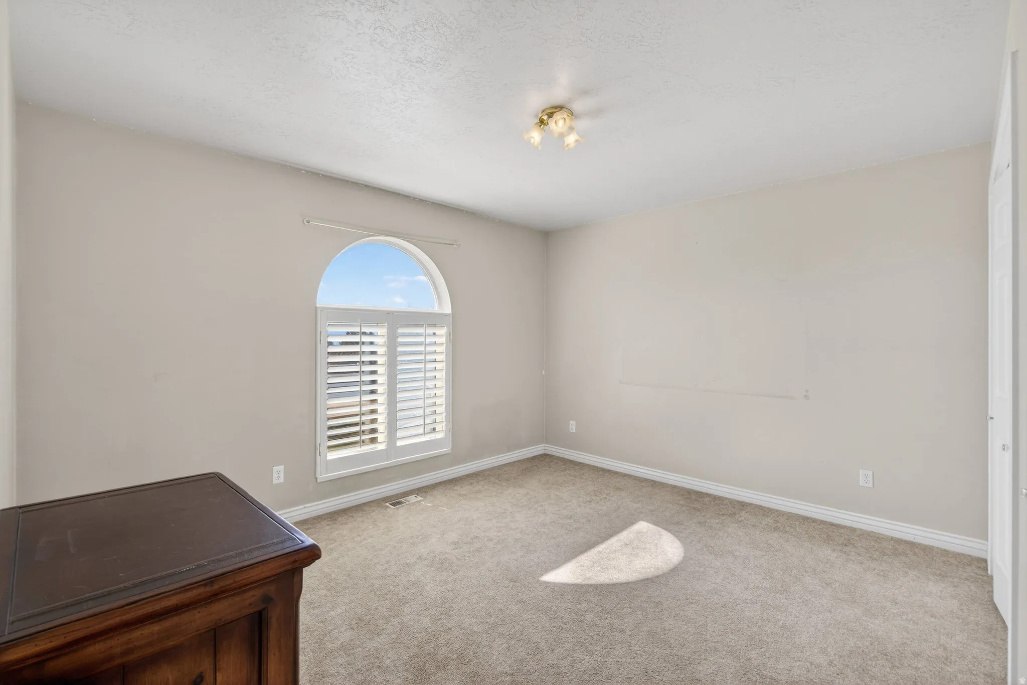 2nd Main floor bedroom with light colored carpet and a textured ceiling