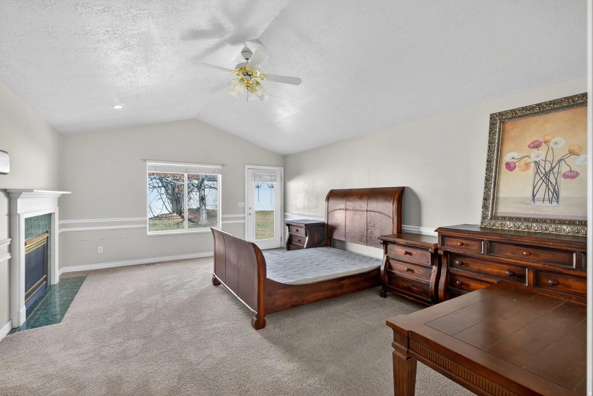 Master Bedroom with access to outside, ceiling fan, a tile fireplace, carpet flooring, and a textured ceiling