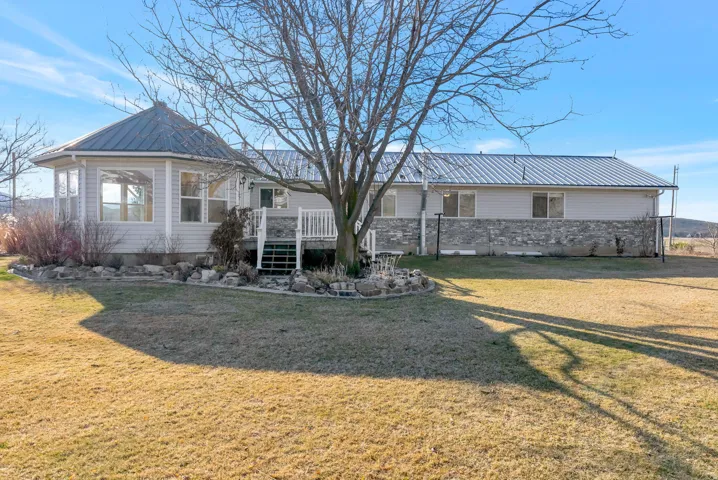 View of back of home with a metal roof, a deck, and sunroom