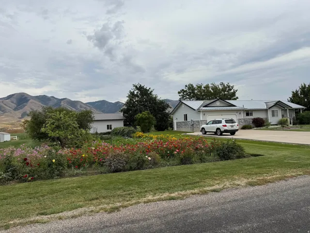 View of green lawn with driveway, a garage, and a mountain view