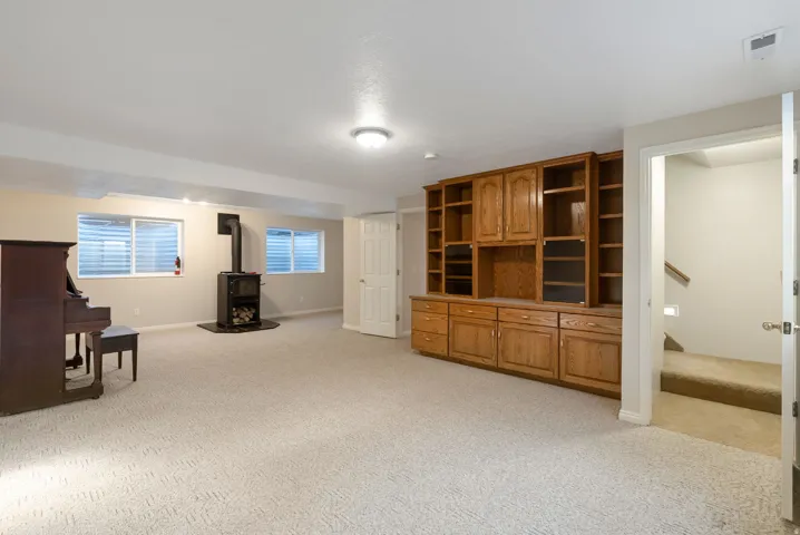 Family room with a wood stove, light carpet, and plenty of natural light
