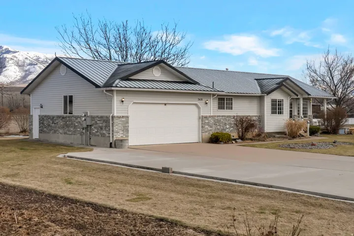 Ranch-style home with a garage, concrete driveway, a metal roof