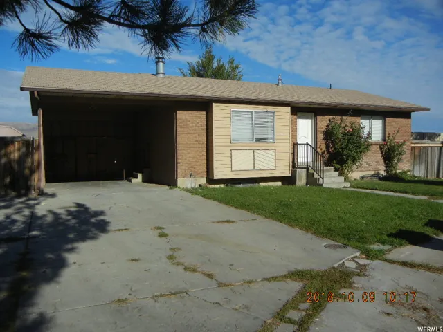 Single story home featuring a front lawn, driveway, brick siding, and a carport