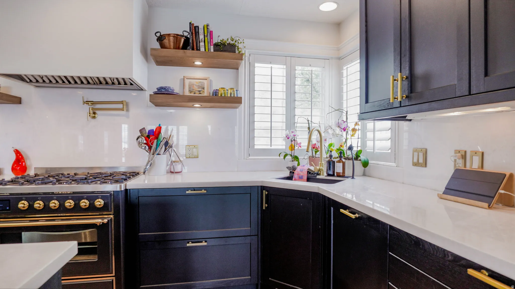 Kitchen featuring gas range oven, light stone countertops, and open shelves