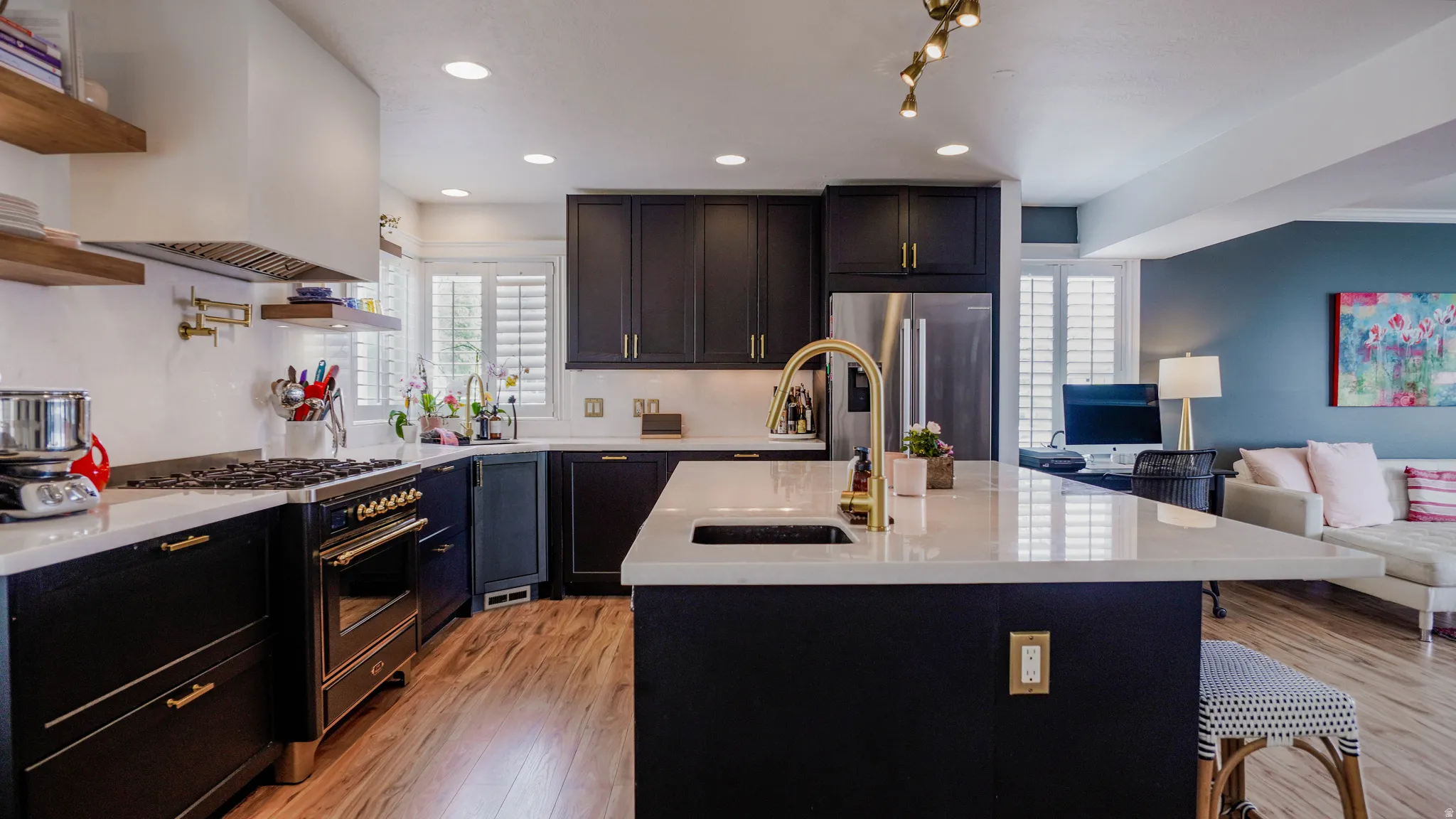 Kitchen with open floor plan, range with gas cooktop, light wood-style floors, light stone counters, and recessed lighting