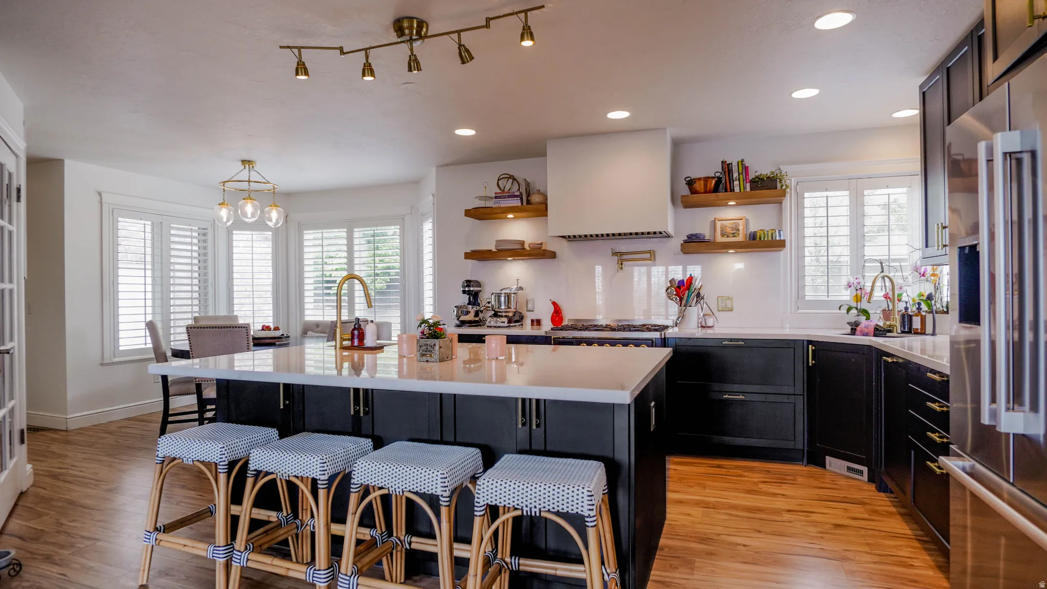 Kitchen featuring dark cabinets, a breakfast bar area, high quality fridge, and light wood-style flooring
