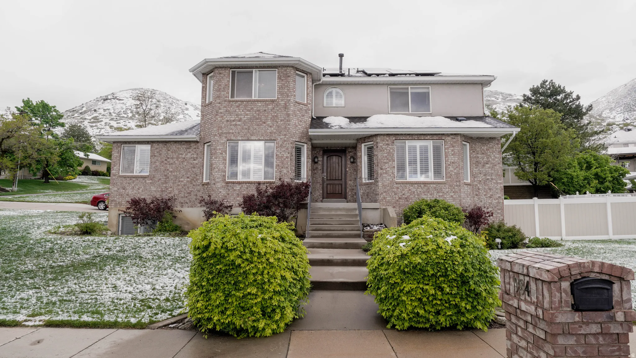 View of front of house featuring a mountain view, roof mounted solar panels, and brick siding