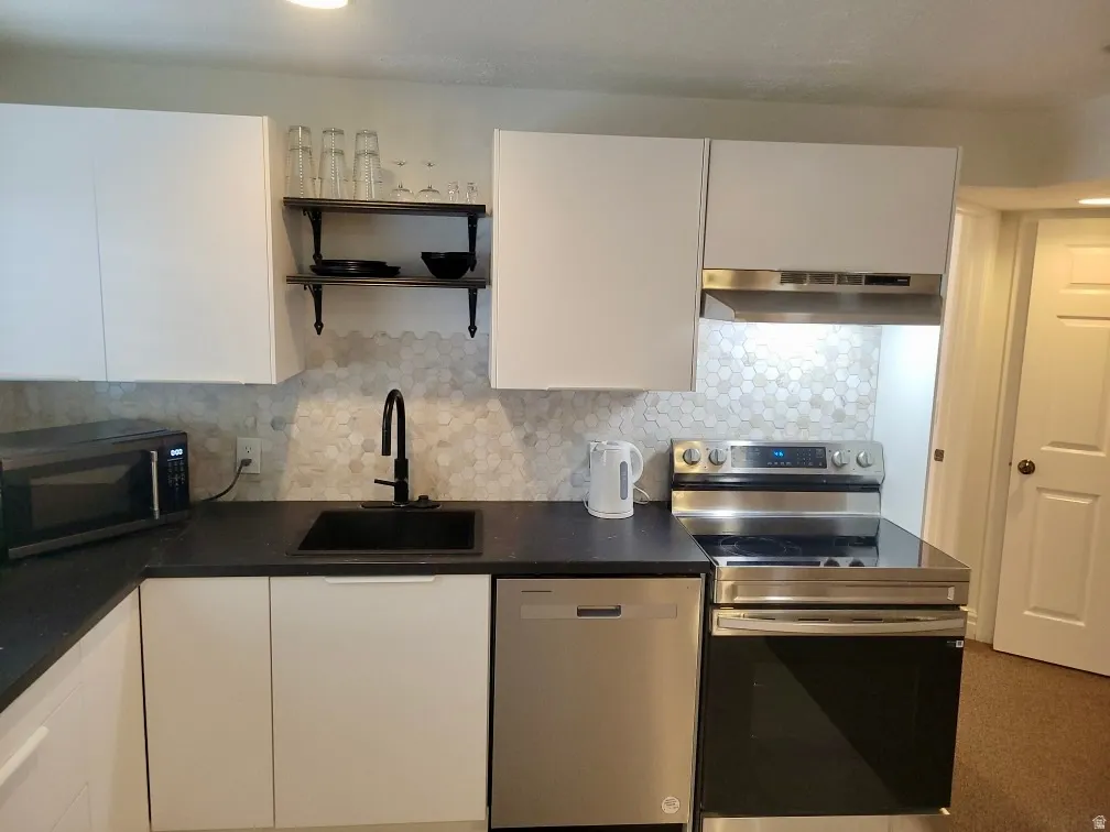 Kitchen featuring stainless steel appliances, white cabinets, tasteful backsplash, and open shelves