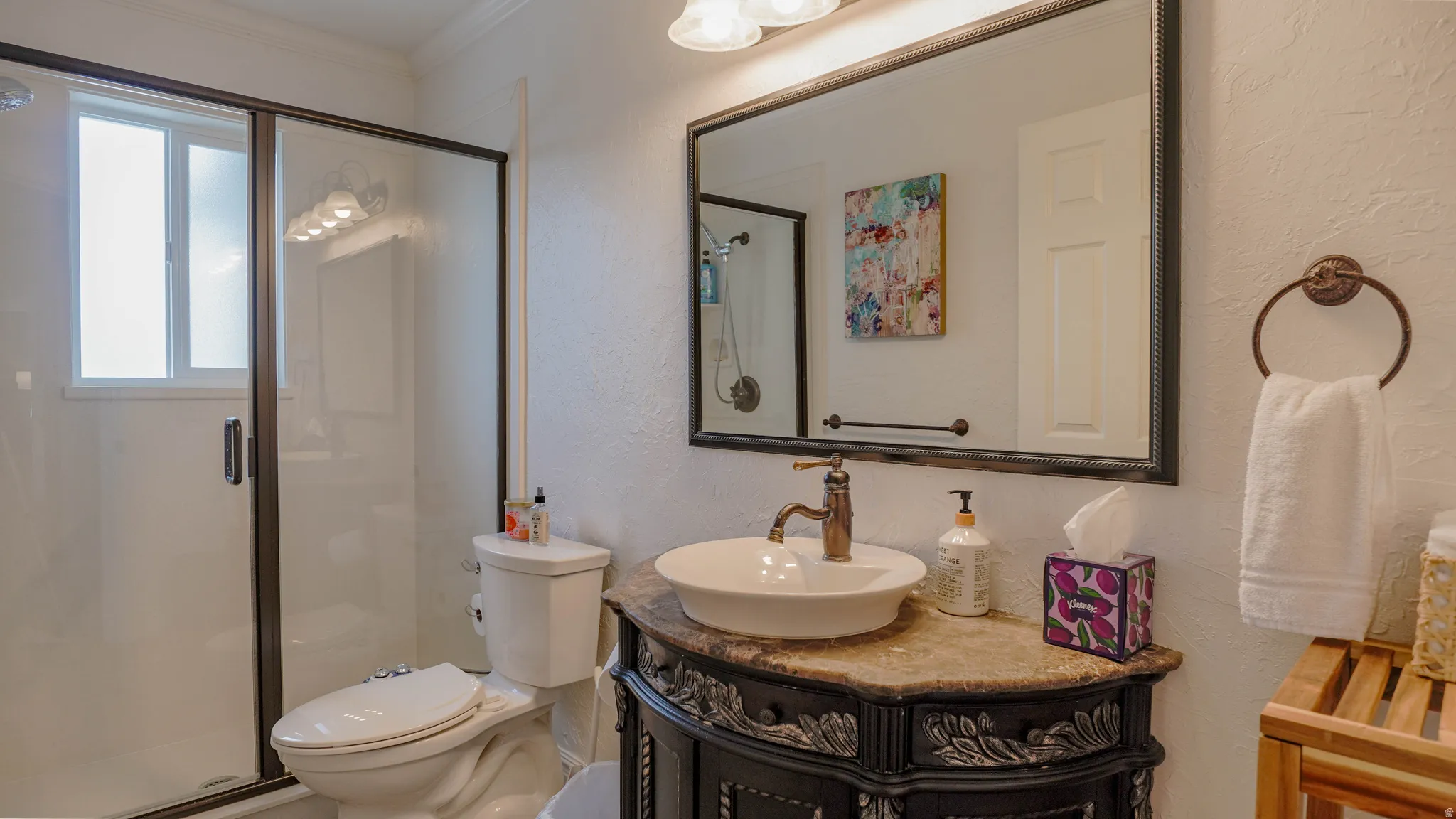 Full bath featuring a textured wall, a stall shower, vanity, and ornamental molding