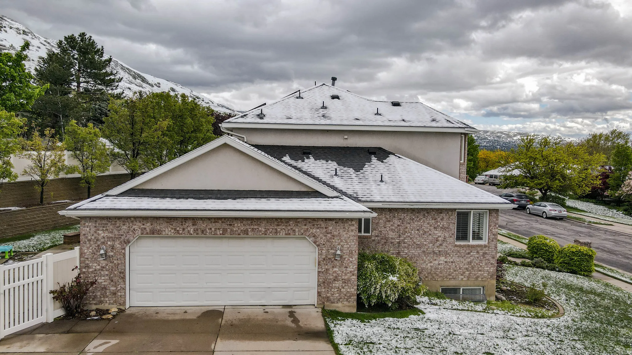 View of side of home with driveway, an attached garage, a shingled roof, and brick siding