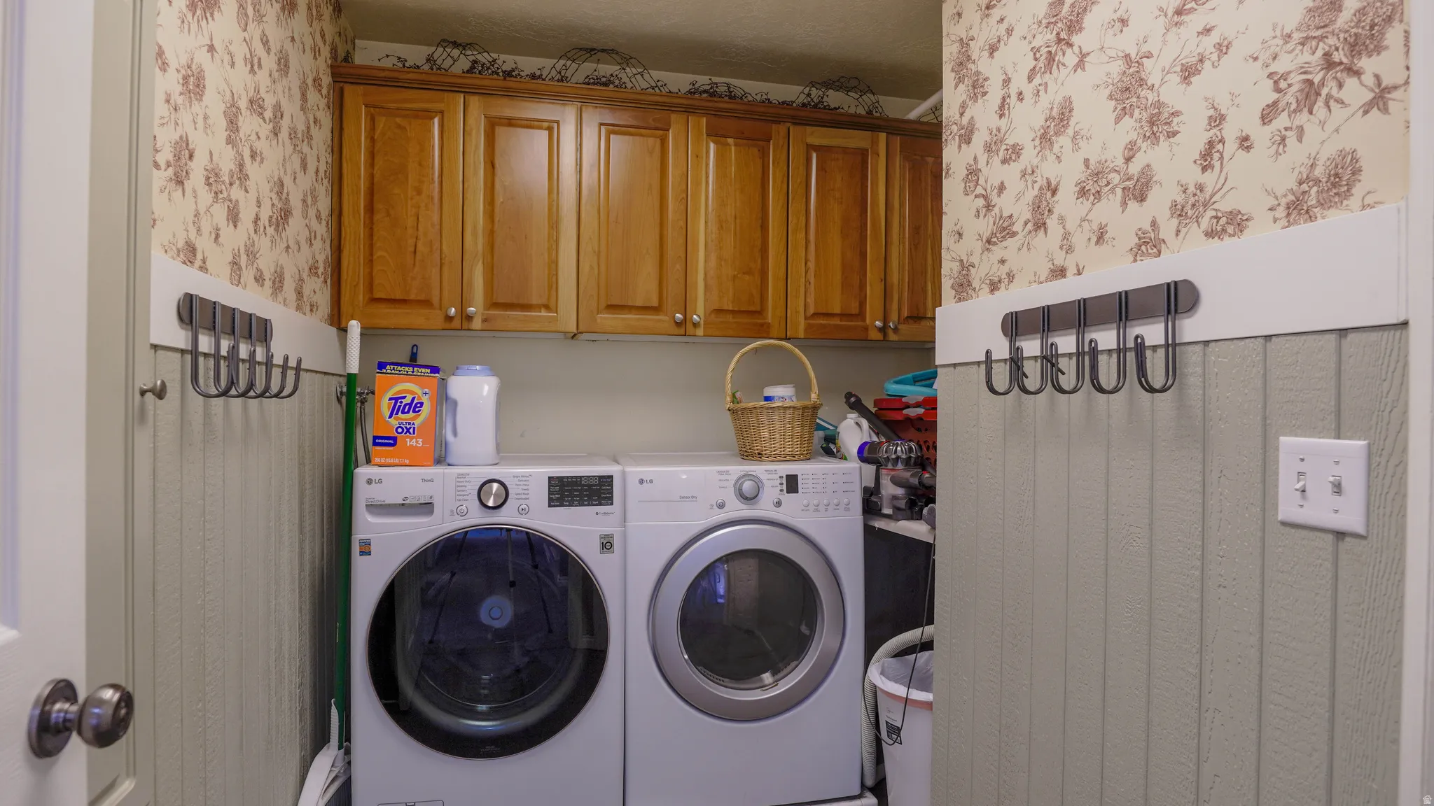 Laundry room featuring wallpapered walls, washer and dryer, and cabinet space