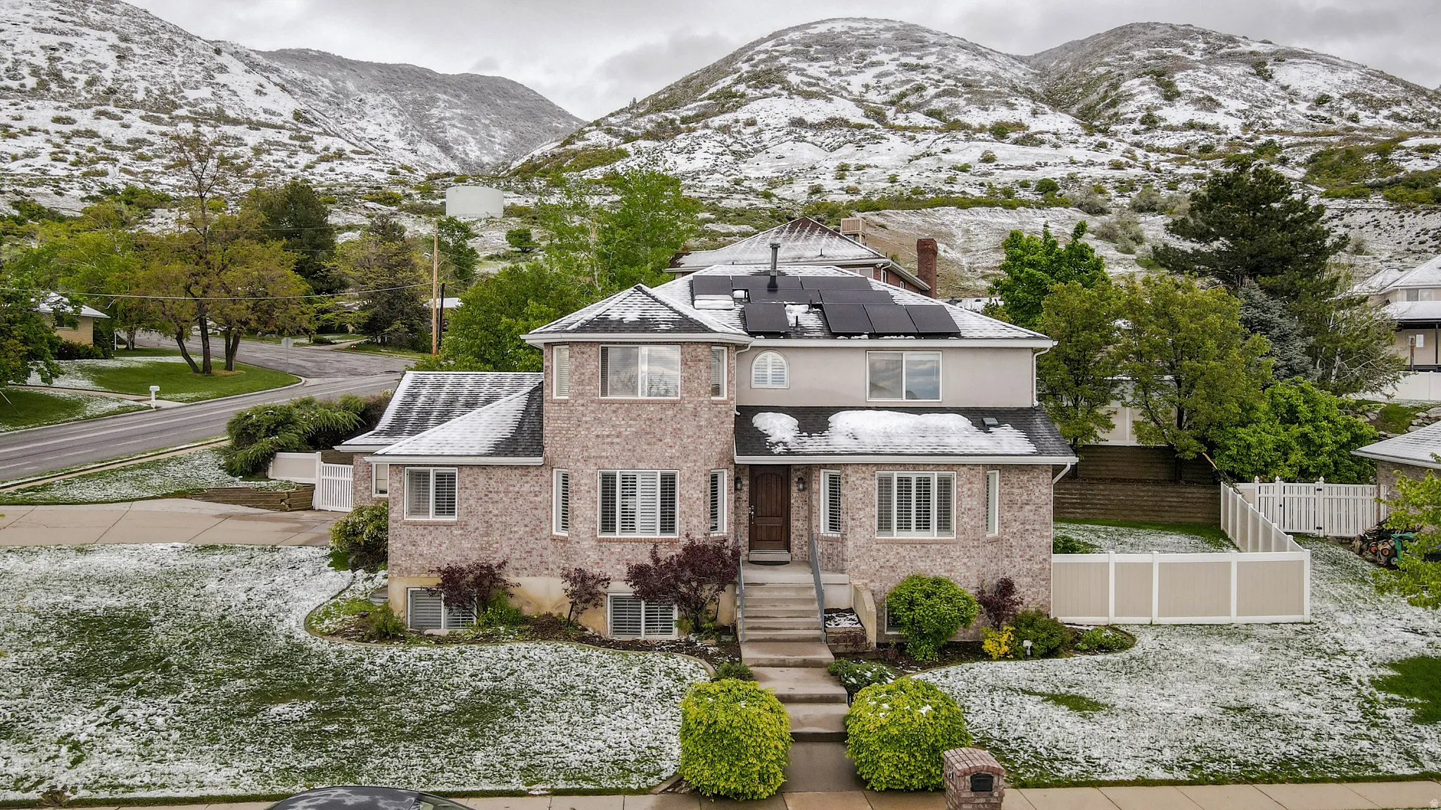 View of front of house featuring solar panels, a mountain view, brick siding, and a chimney