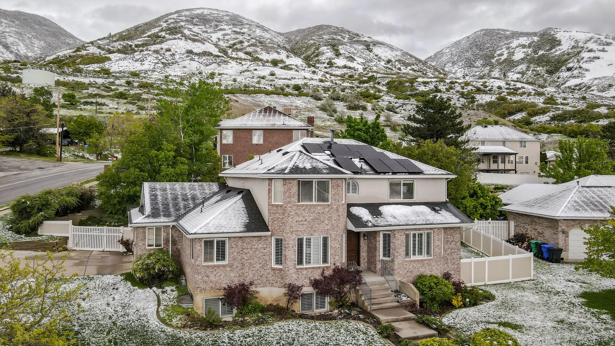 View of front of house featuring a gate, a mountain view, solar panels, and brick siding