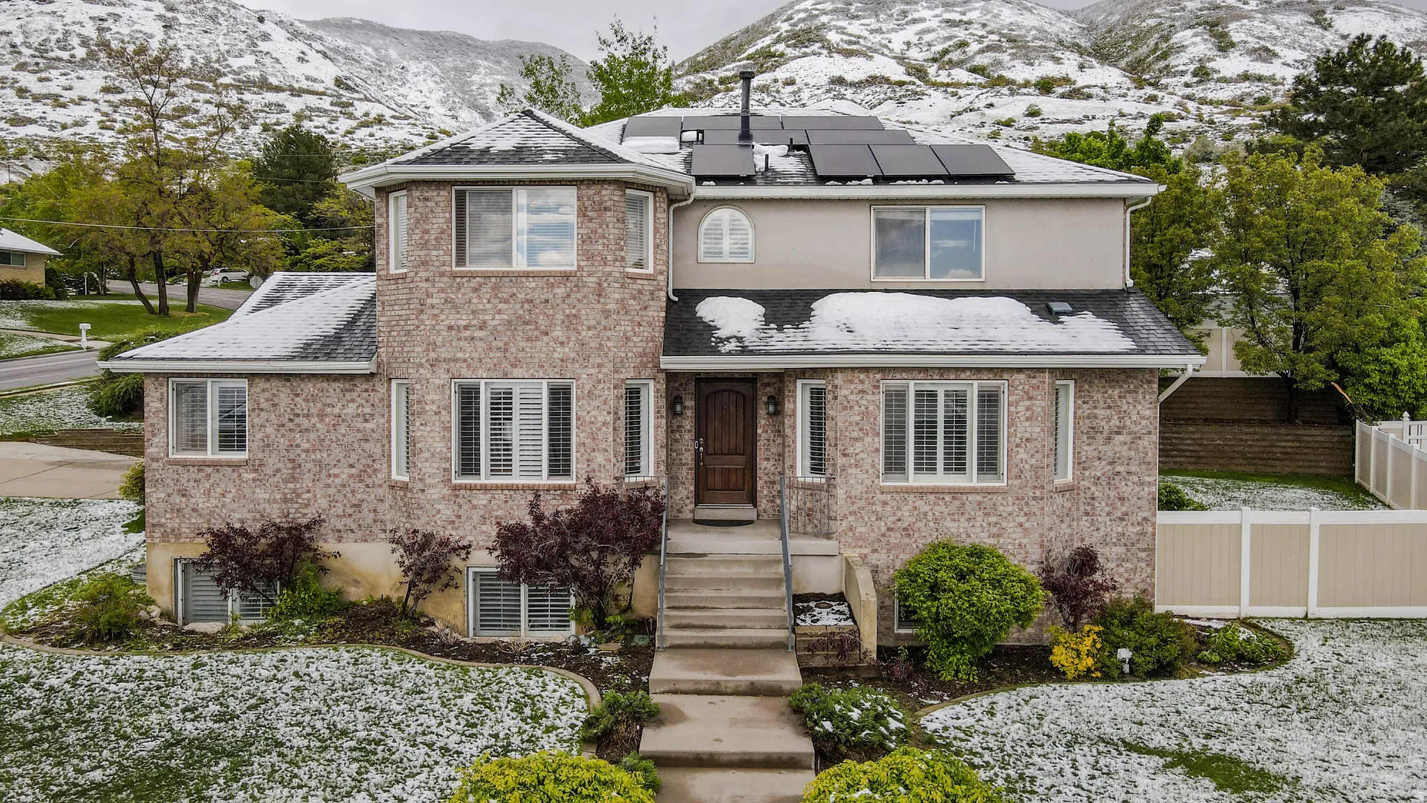 View of front facade featuring a mountain view, solar panels, and brick siding