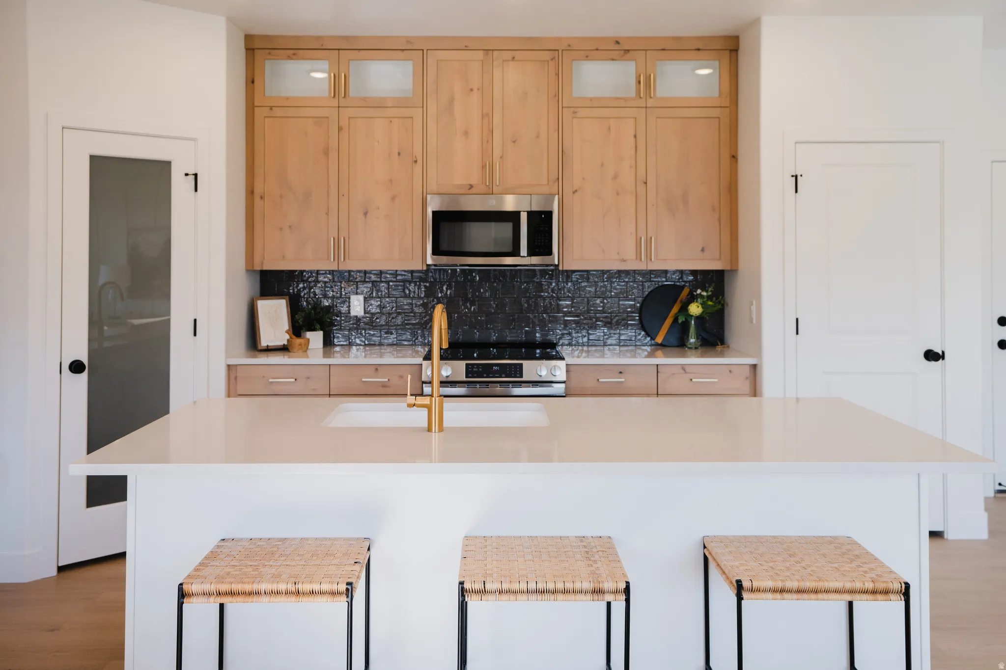 Kitchen featuring light wood finish cabinetry, an island with sink, stainless steel appliances, and light wood-type flooring