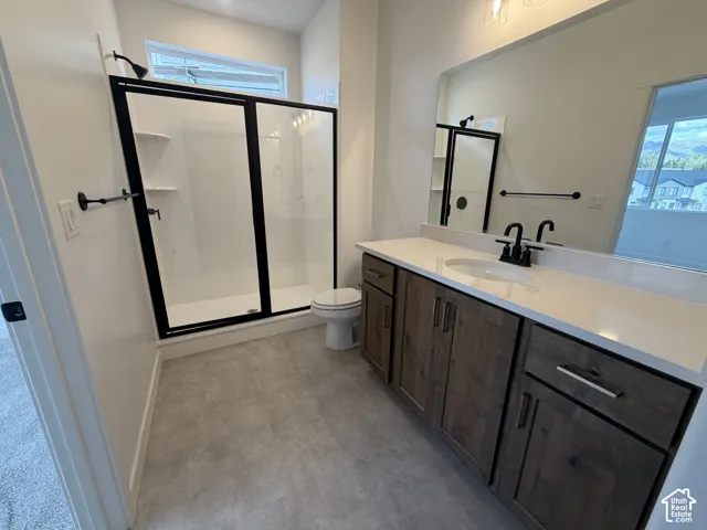 Spa-inspired primary bathroom featuring a double vanity with quartz countertop and wood-finish cabinetry, frameless glass-enclosed walk-in shower with tile surround, and polished chrome fixtures throughout