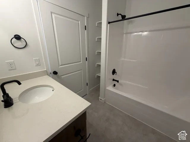 Bathroom featuring a single vanity with an integrated sink, solid surface countertop, and matte black fixtures