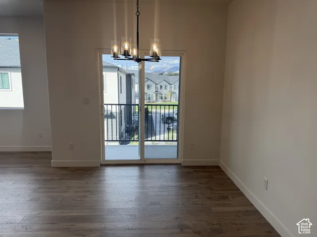 Wood-finish flooring, sliding glass door, modern chandelier, and white wall finishes