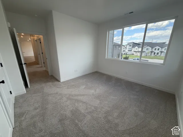 Expansive window, neutral wall paint, gray carpeting, white trim, and black door hardware
