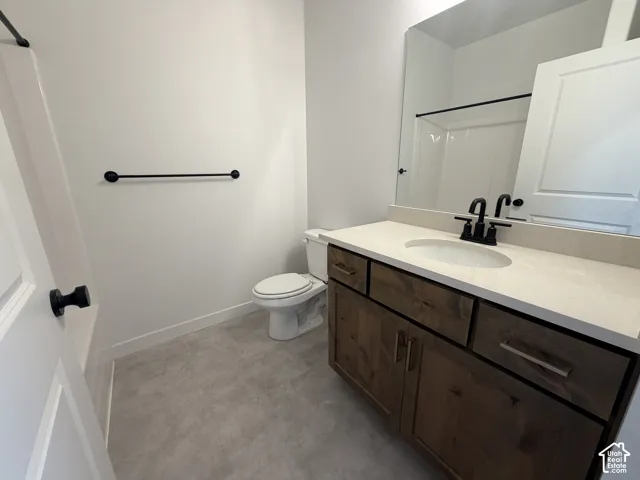 Bathroom featuring a wood-finish vanity with a light-toned countertop, rectangular undermount sink, and matte black hardware