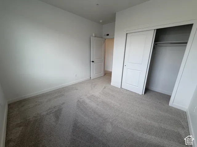 Neutral wall finishes, recessed lighting, and light-toned carpet flooring