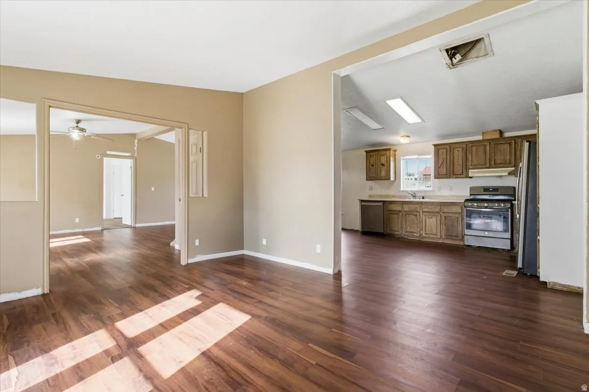 Unfurnished living room featuring dark wood-style floors and a ceiling fan