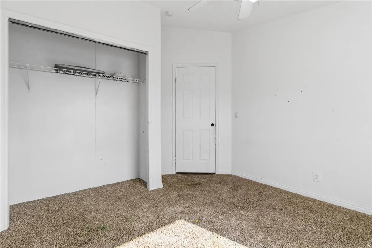 Unfurnished bedroom featuring carpet flooring, a closet, and a ceiling fan