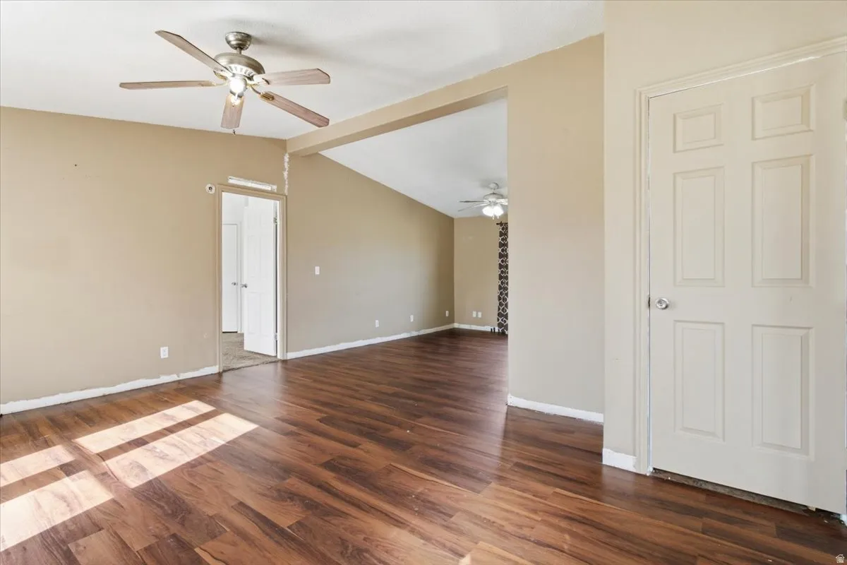 Unfurnished room featuring a ceiling fan and dark wood-style floors