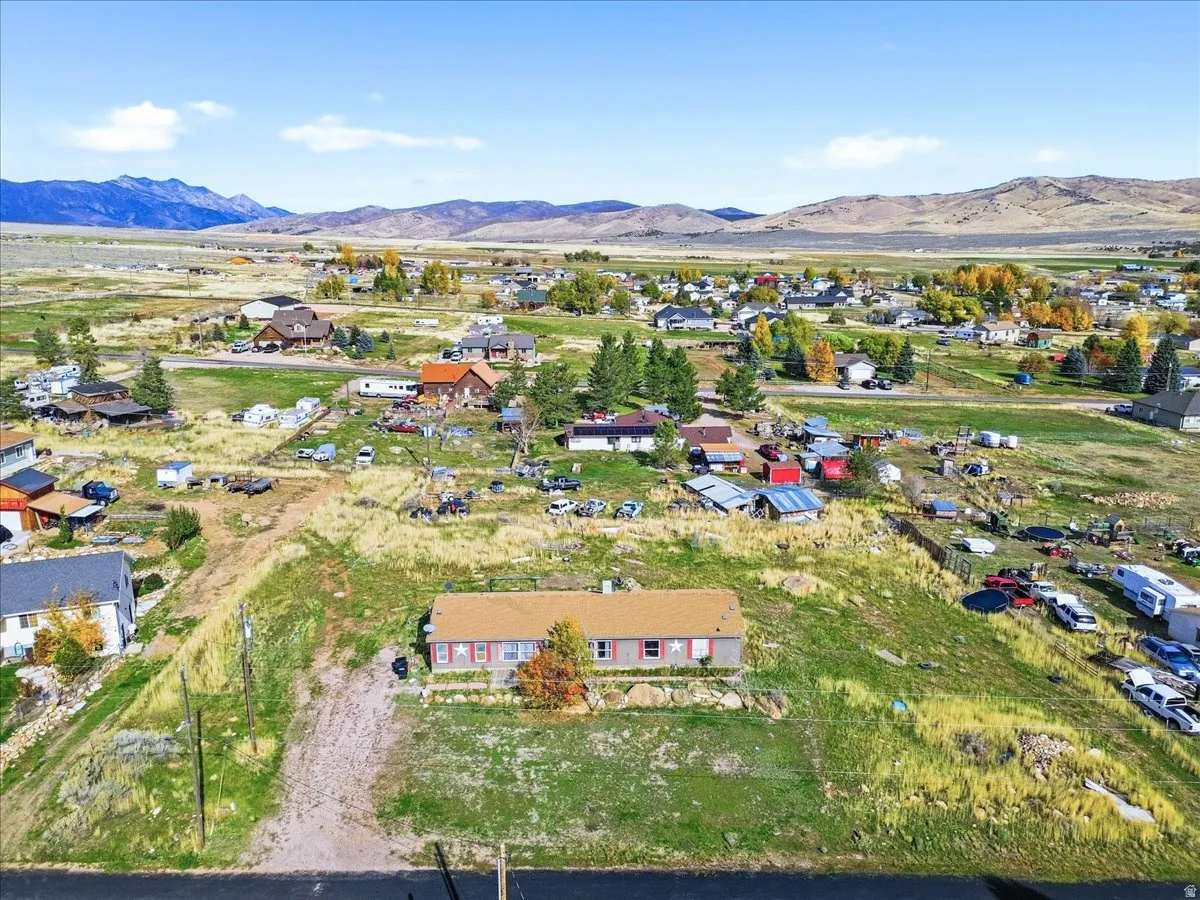 Aerial view of property and surrounding area featuring a mountainous background and nearby suburban area