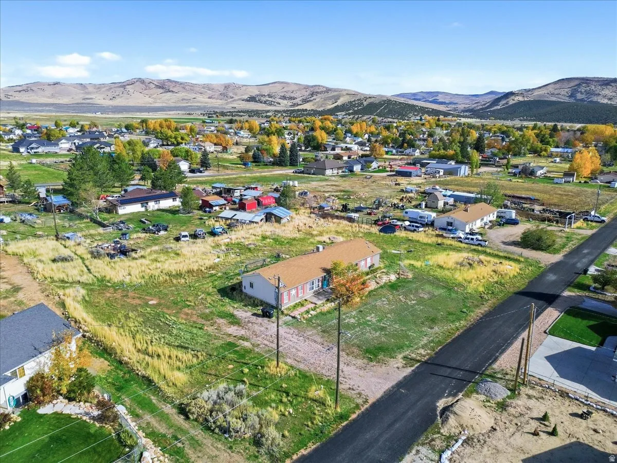 Aerial view of property and surrounding area featuring a mountain backdrop and nearby suburban area