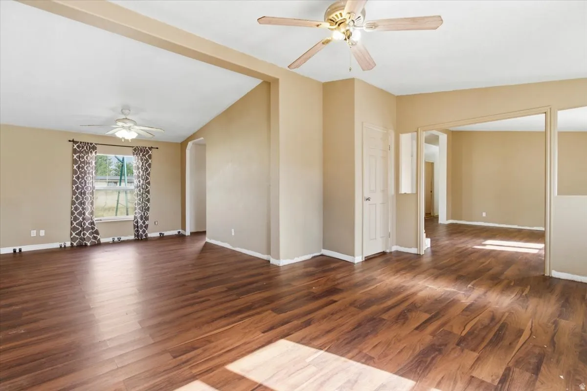 Unfurnished room with a ceiling fan, dark wood-type flooring, and vaulted ceiling
