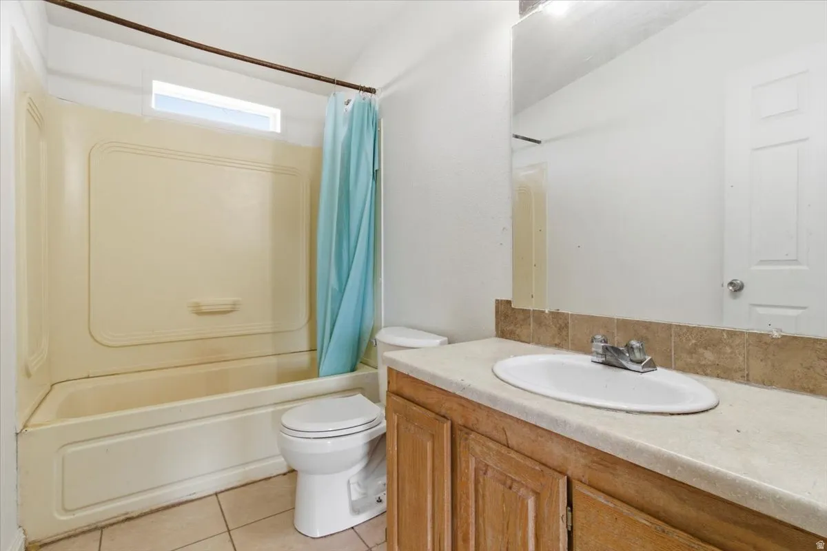 Bathroom with vanity, shower / bathtub combination with curtain, and light tile patterned floors