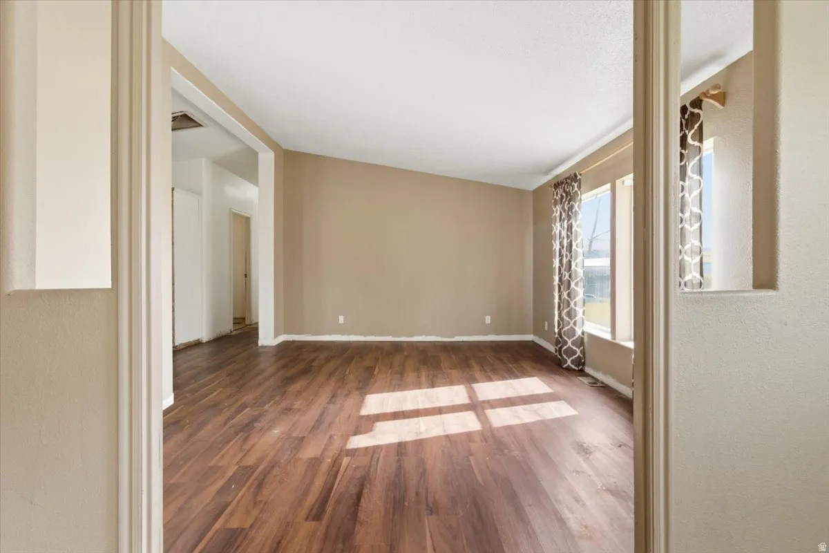 Empty room with dark wood-style flooring and baseboards
