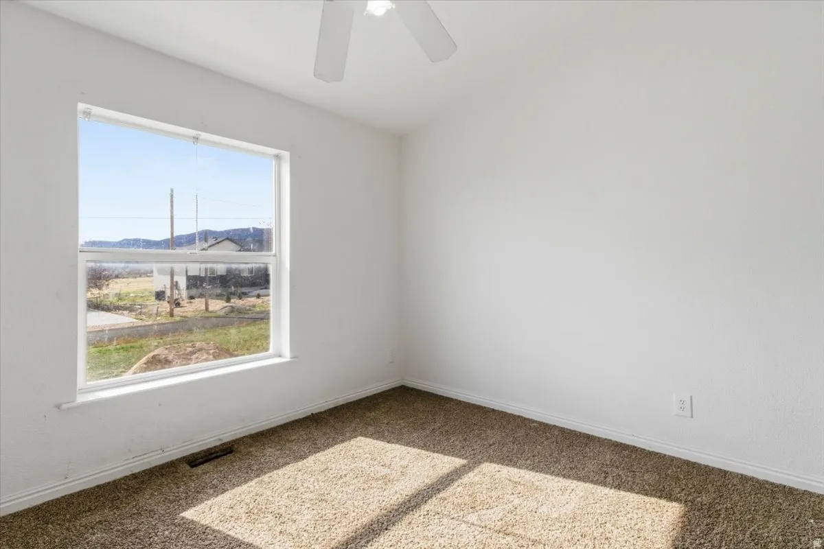 Carpeted spare room featuring a mountain view and ceiling fan