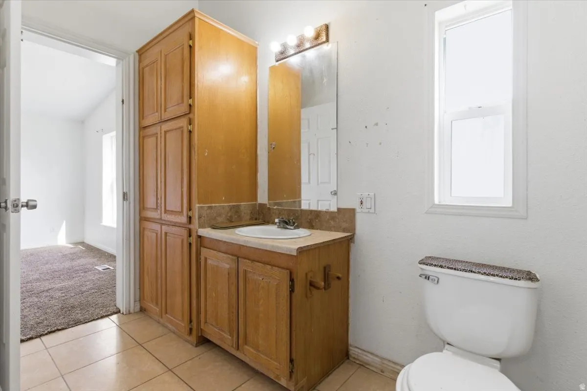Bathroom featuring vanity, light tile patterned floors, and vaulted ceiling