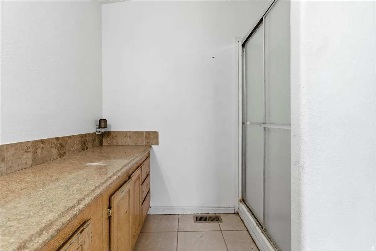 Bathroom featuring vanity, a stall shower, light tile patterned flooring, and a textured wall