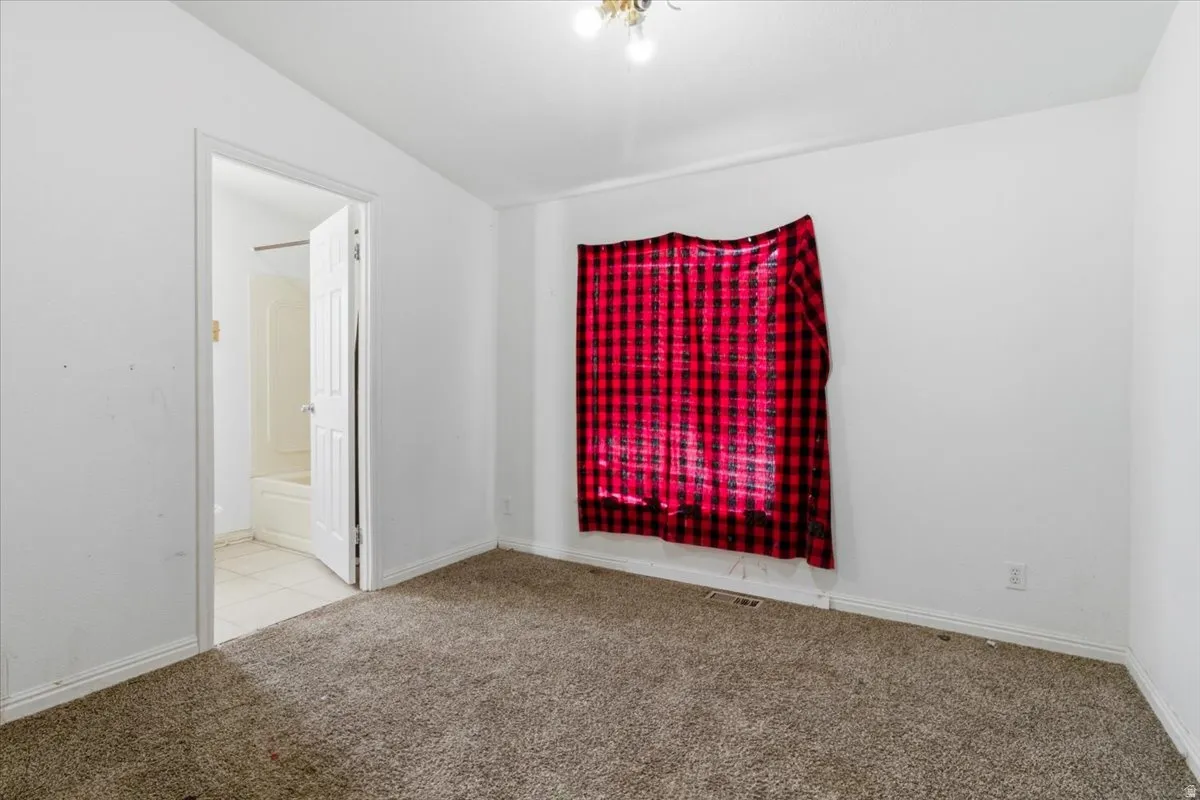 Spare room featuring light carpet and lofted ceiling