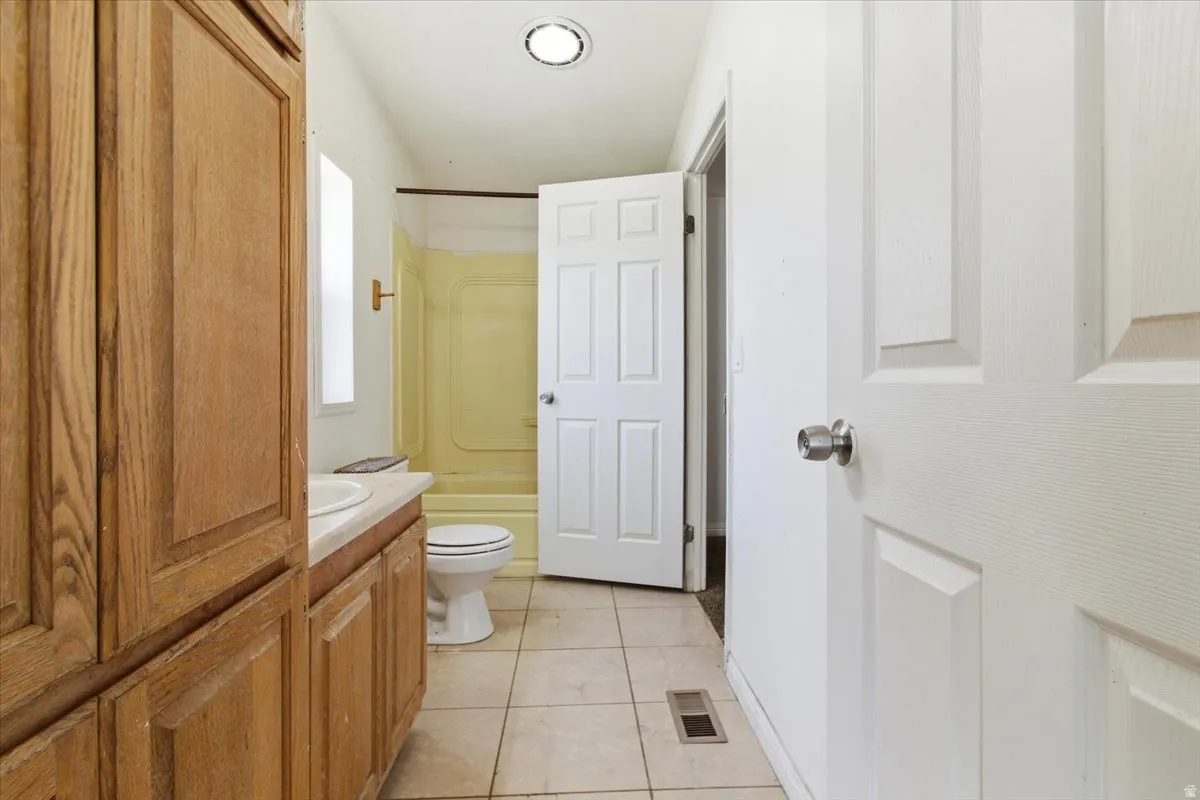 Full bath featuring vanity, light tile patterned floors, and tub / shower combination