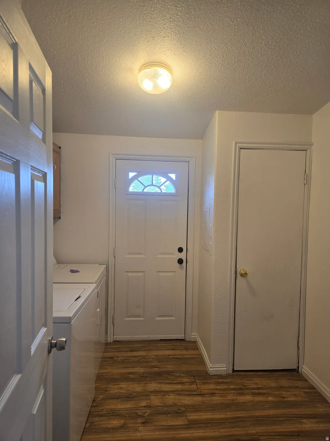 Laundry room featuring a textured ceiling, dark wood finished floors, cabinet space, and independent washer and dryer