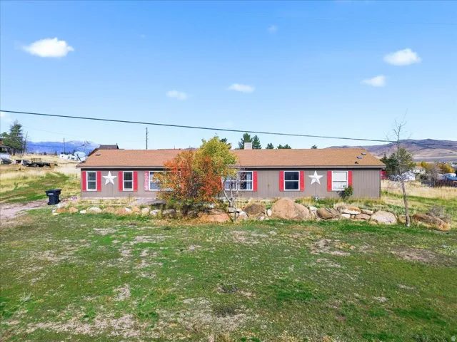 View of front facade featuring a mountain view, a front yard, and a shingled roof
