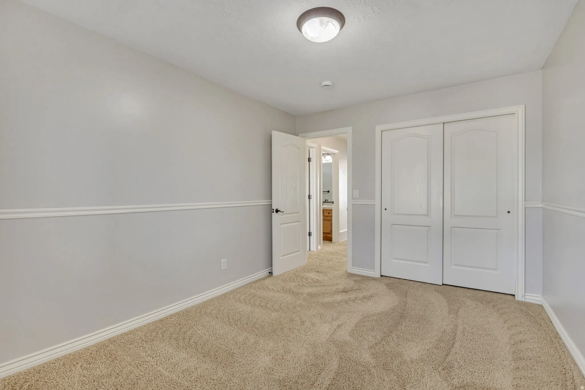 Unfurnished bedroom with light colored carpet and a closet