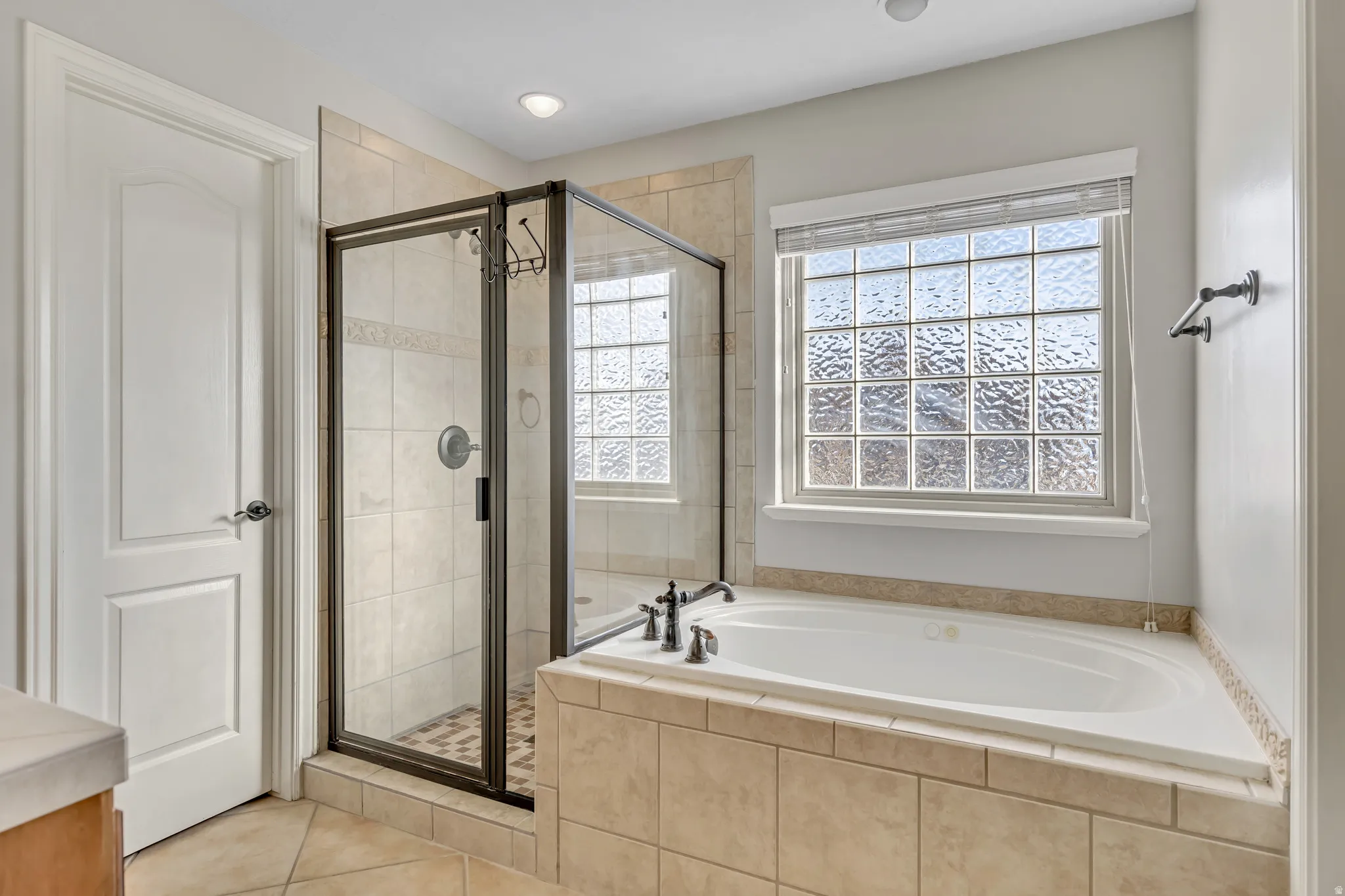 Bathroom featuring a garden tub, a shower stall, light tile patterned floors, and vanity