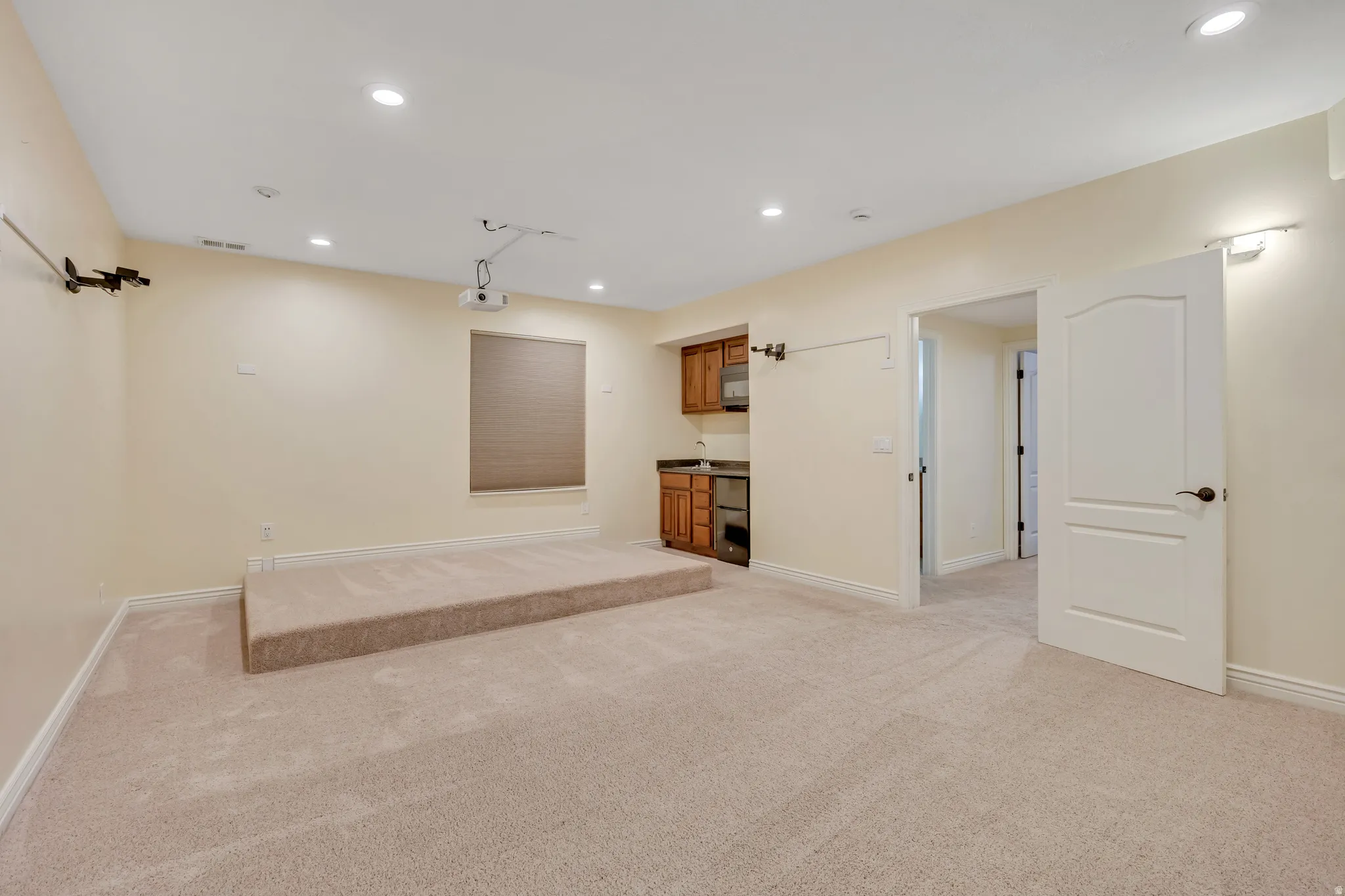 Basement with recessed lighting, light colored carpet, and bar with sink
