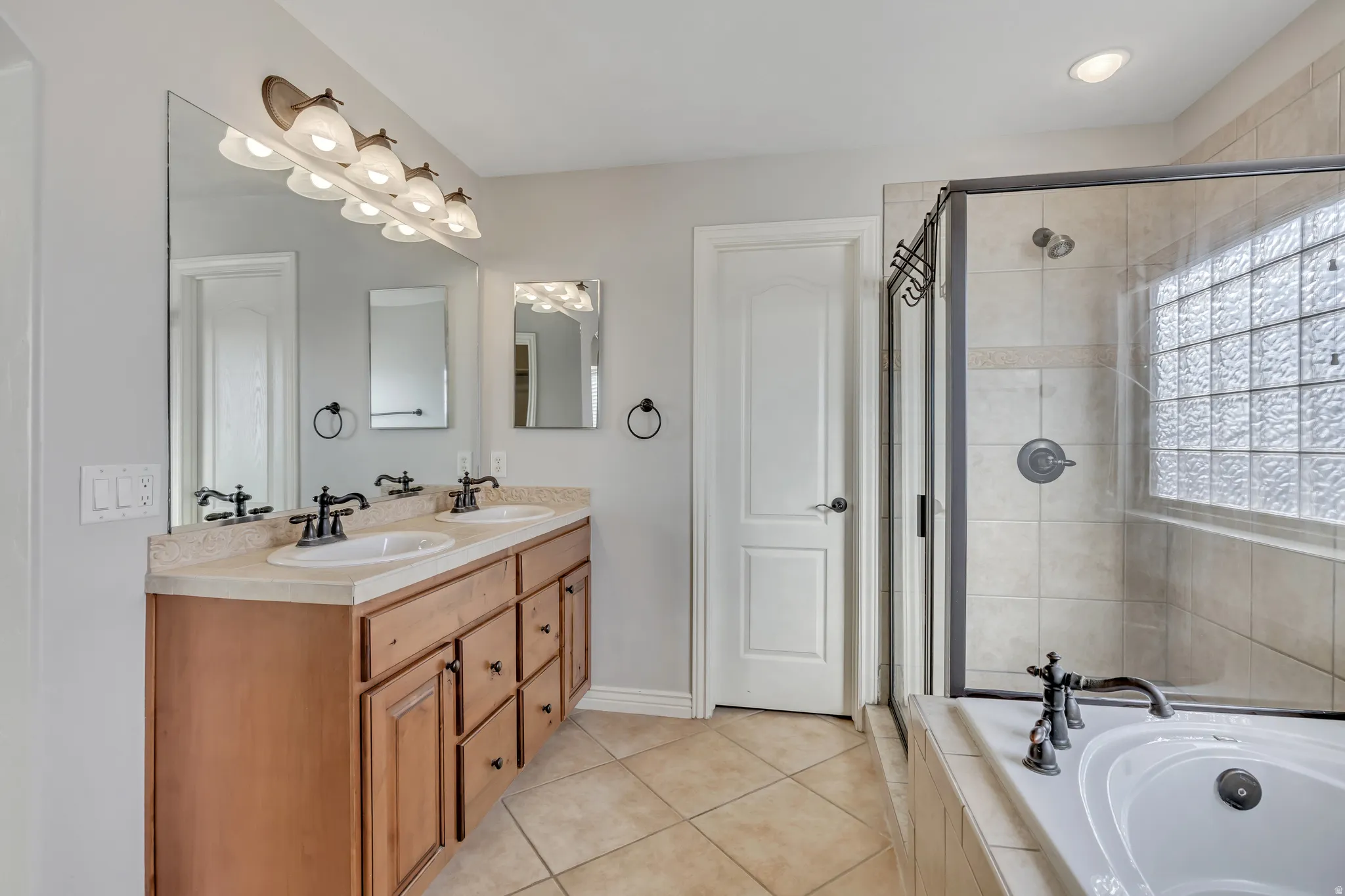 Bathroom with double vanity, a bath, light tile patterned flooring, and a stall shower