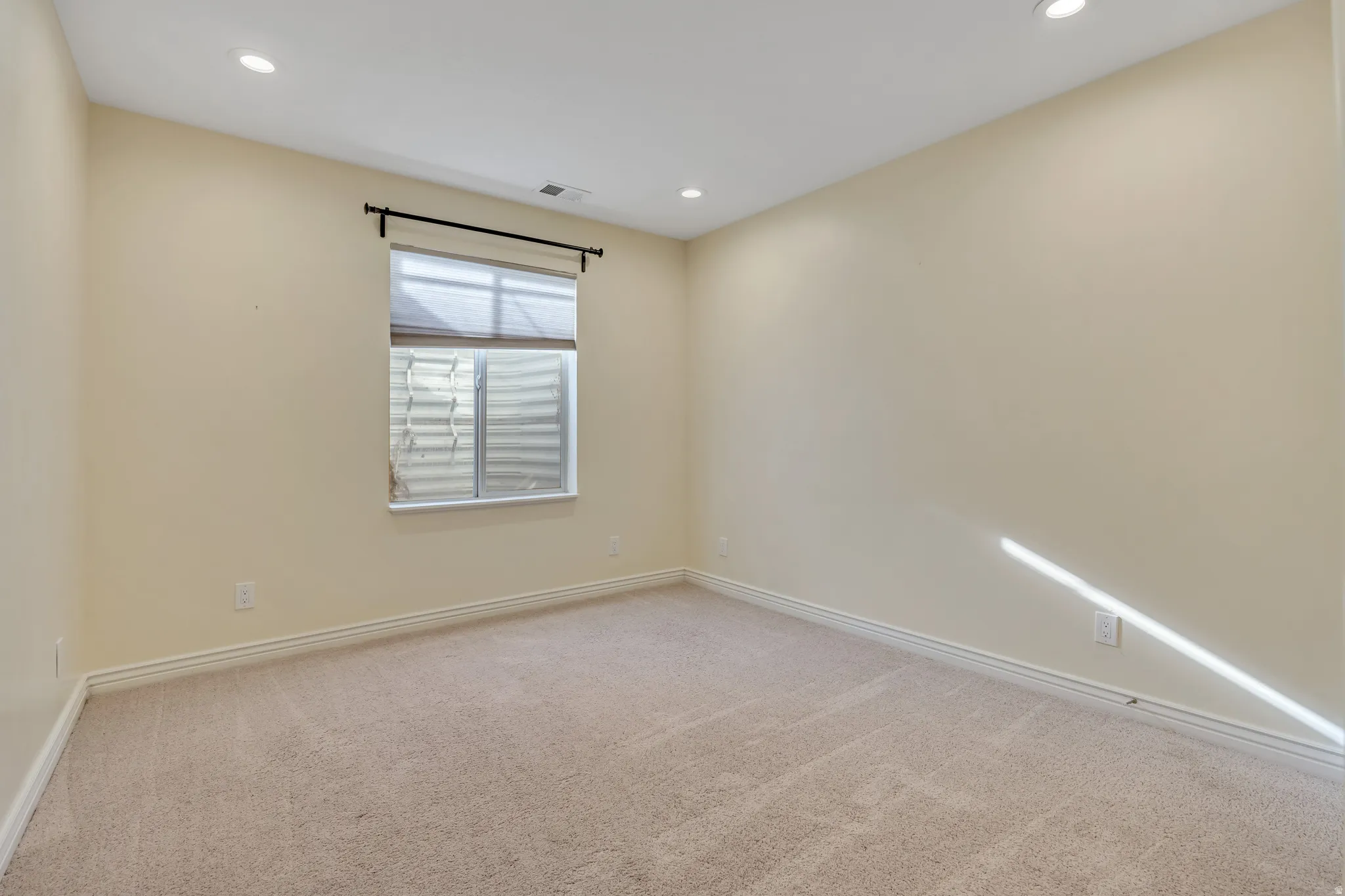 Spare room featuring light colored carpet and recessed lighting