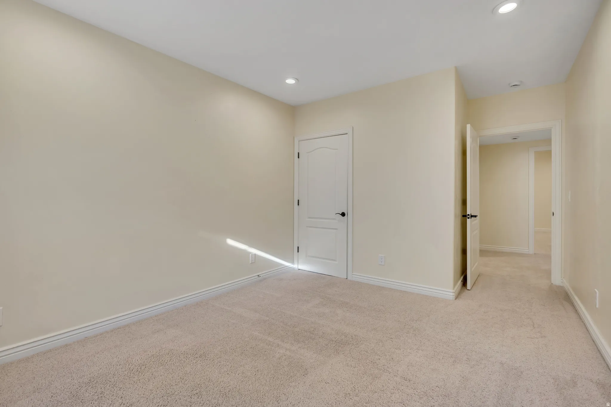 Empty room with light colored carpet and recessed lighting
