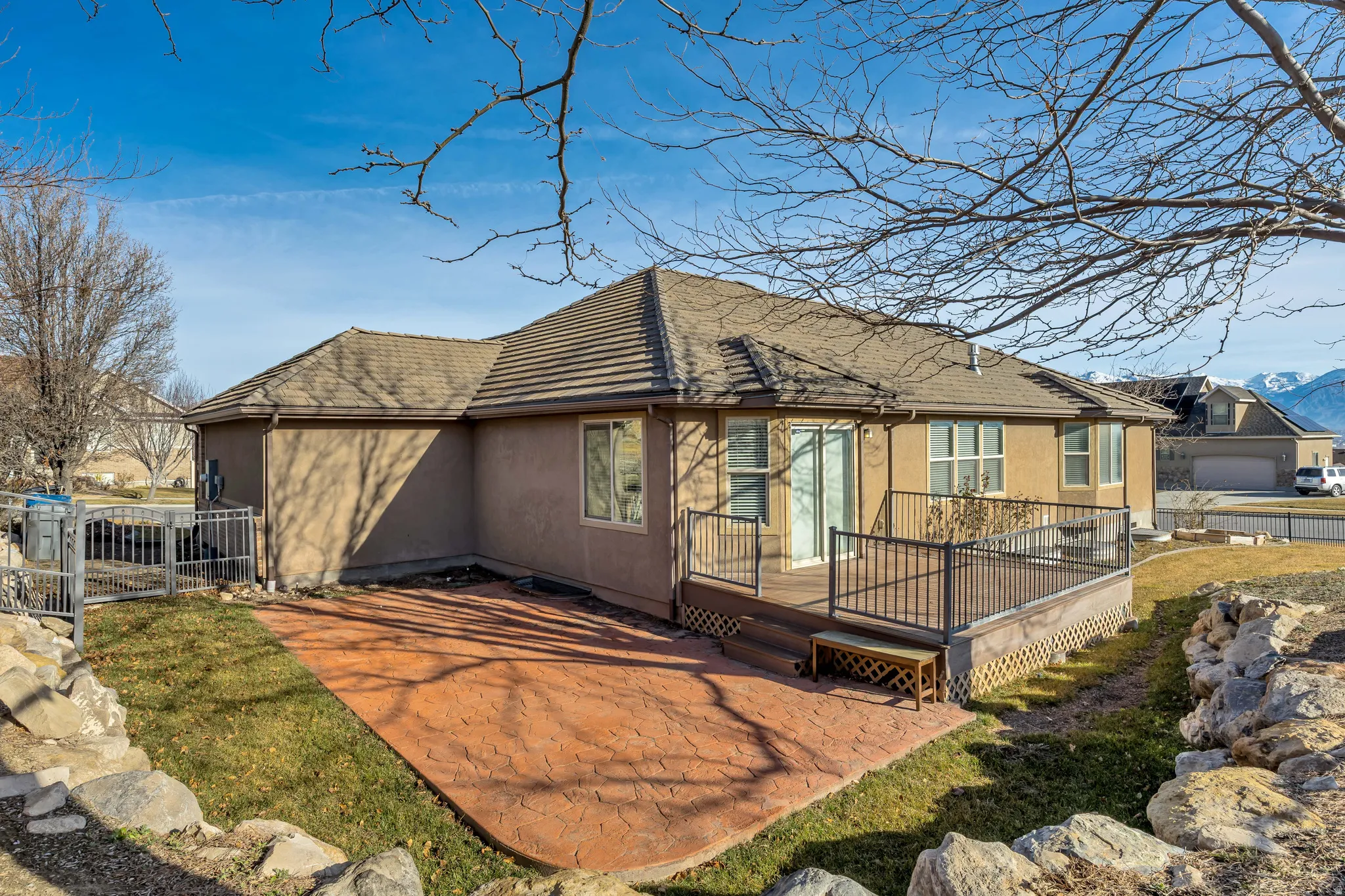 Rear view of property with a patio area, stucco siding, a deck, a gate, and roof with shingles