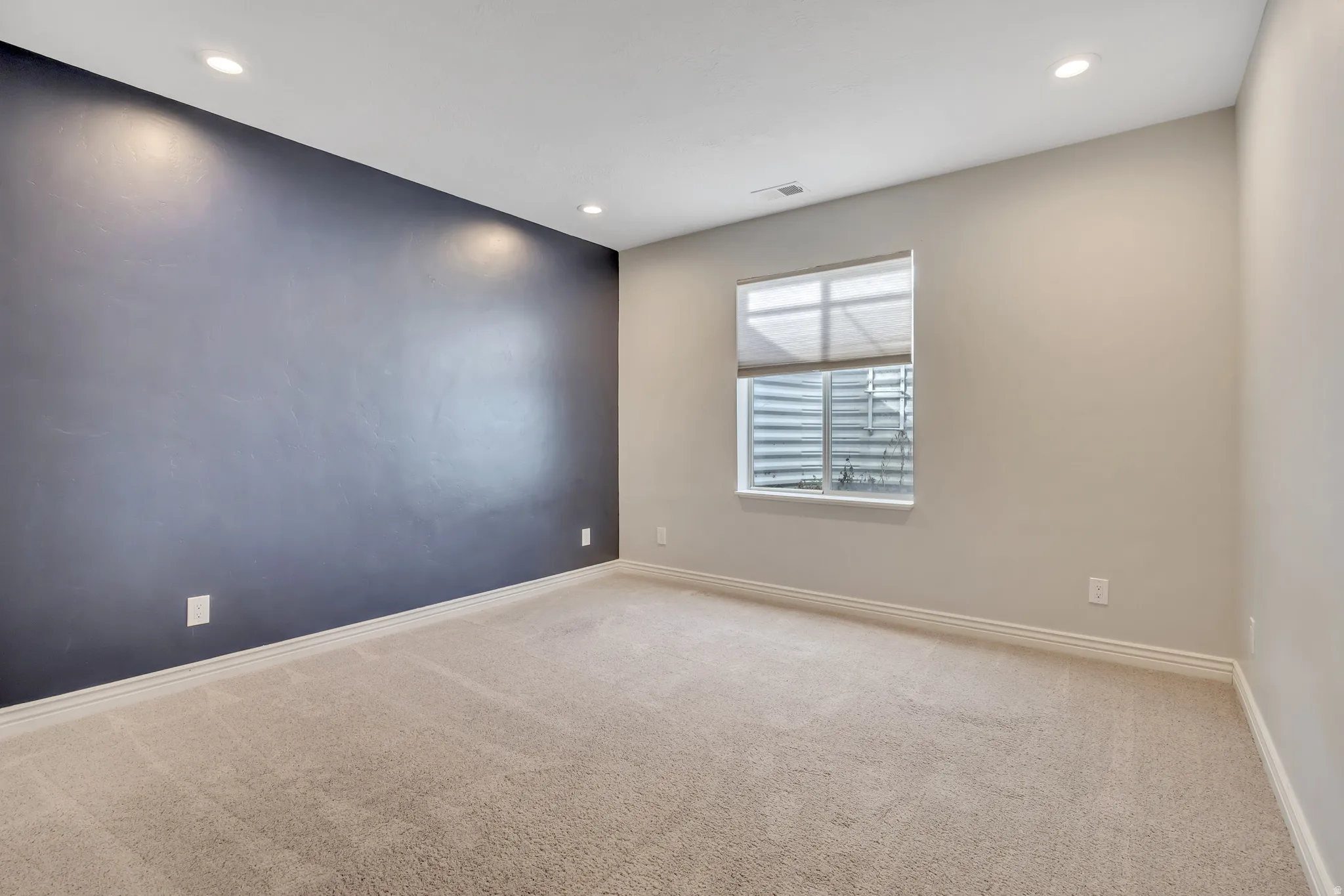 Empty room with light carpet and recessed lighting