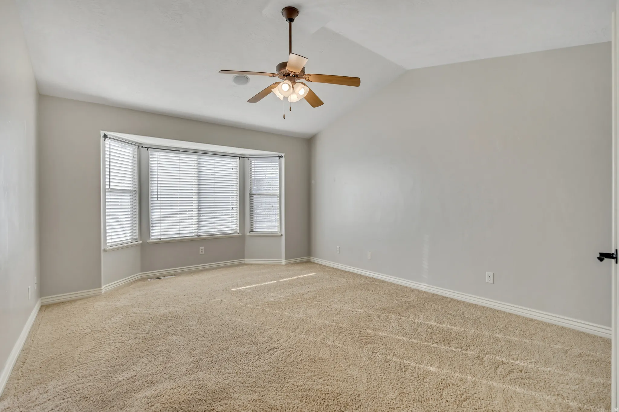 Unfurnished room featuring light carpet, a ceiling fan, and lofted ceiling