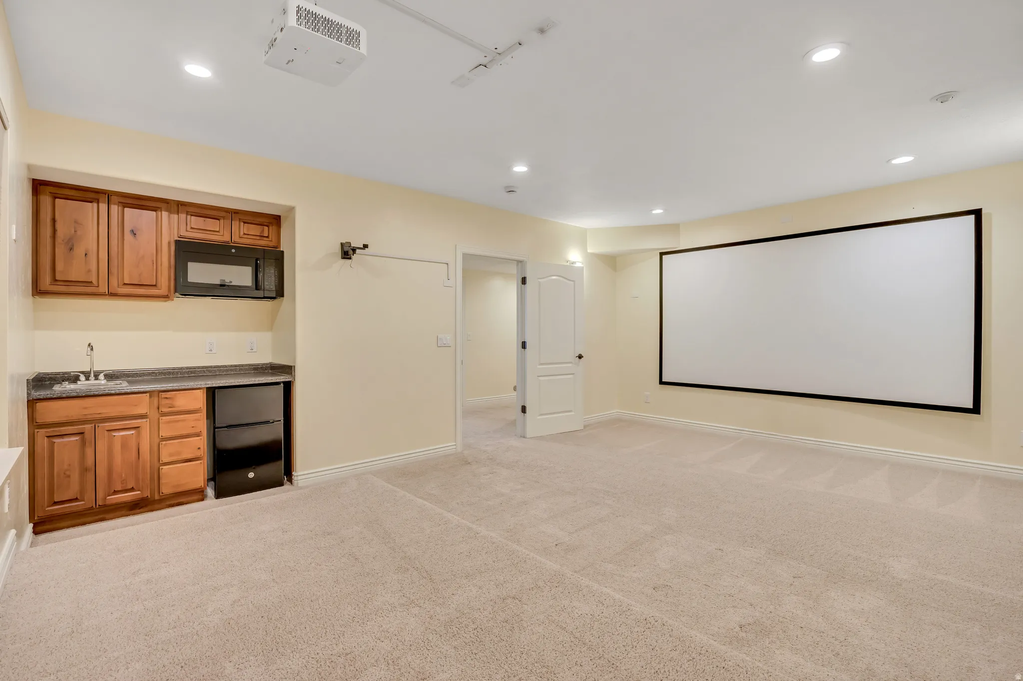 Home theater room featuring light carpet, recessed lighting, and bar with sink